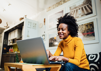 woman sitting on couch working on laptop.